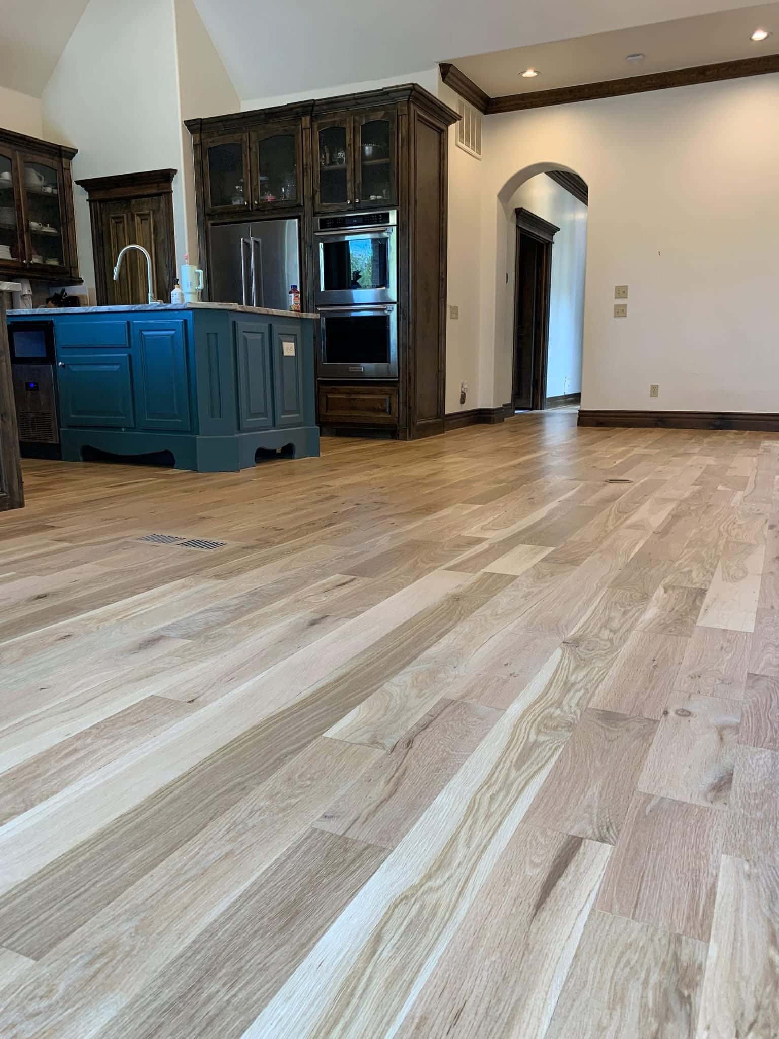 Wide plank oak hardwood flooring installation in an open-concept residential living space.