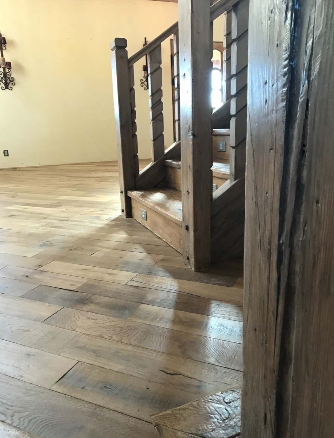 Custom hardwood staircase installation with detailed wood trim and iron balusters.